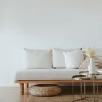 Minimalist living room with a neat sofa, tidy cushions, and a simple décor reflecting a decluttered space, emphasizing the calm and order of an stress-free environment. declutter for your wellbeing